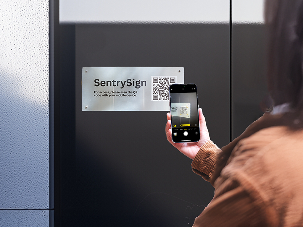 A visitor scanning a QR code on a sign to gain entry to a property.